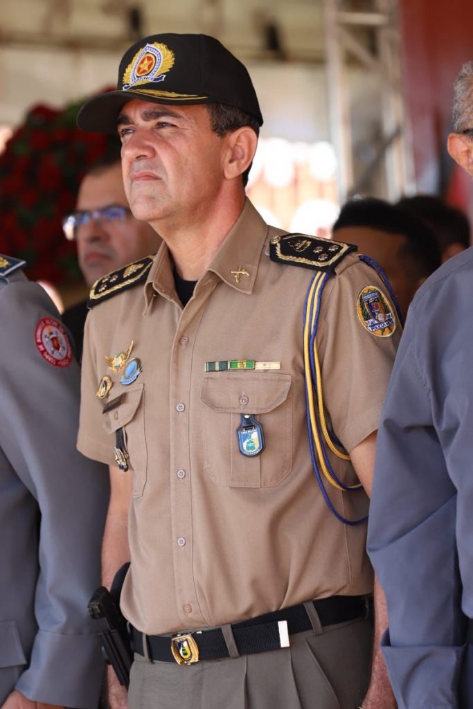 Portal Jaciara Barros – A comandante, de uniforme e boné, está ao ar livre entre outras pessoas, com expressão séria e olhando para a frente. – Portal Jaciara Barros
