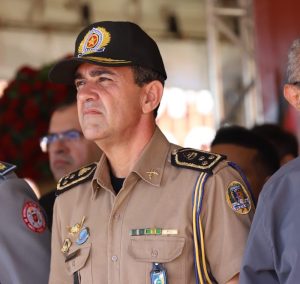 Portal Jaciara Barros – A comandante, de uniforme e boné, está ao ar livre entre outras pessoas, com expressão séria e olhando para a frente. – Portal Jaciara Barros