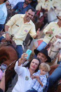 Portal Jaciara Barros – Homem a cavalo faz sinal de positivo enquanto mulher e criança tiram selfie em evento de agronegócio no Tocantins. – Portal Jaciara Barros