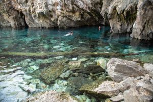 Portal Jaciara Barros – Os turistas nadam nas águas cristalinas da Lagoa do Japonês, rodeada por rochas e reconhecida como atrativo turístico local. – Portal Jaciara Barros