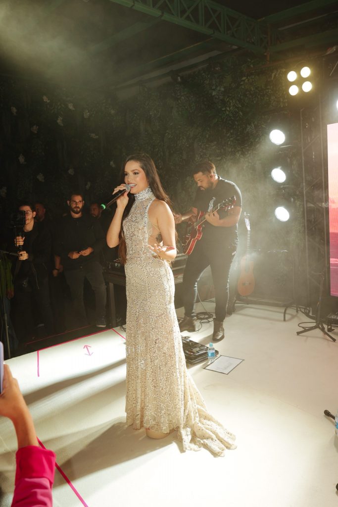 Portal Jaciara Barros – Juliette, usando um vestido cintilante e sapatilhas Anacapri, se apresenta com uma banda sob as luzes brilhantes do palco. – Portal Jaciara Barros