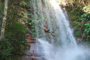Portal Jaciara Barros – Turista equipado com capacete prático rapel próximo a uma alta cachoeira em Palmas, evidenciando o potencial turístico local. – Portal Jaciara Barros