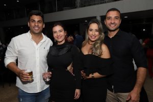 Portal Jaciara Barros – Quatro adultos posam em evento interno; dois seguram bebidas. Todos vestem preto e branco em estilo semi-formal inspirado no soldado moderno. – Portal Jaciara Barros