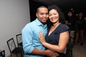 Portal Jaciara Barros – Um homem e uma mulher, sendo um deles vestido de soldado, posam sorrindo em meio a um animado evento social em ambiente interno. – Portal Jaciara Barros