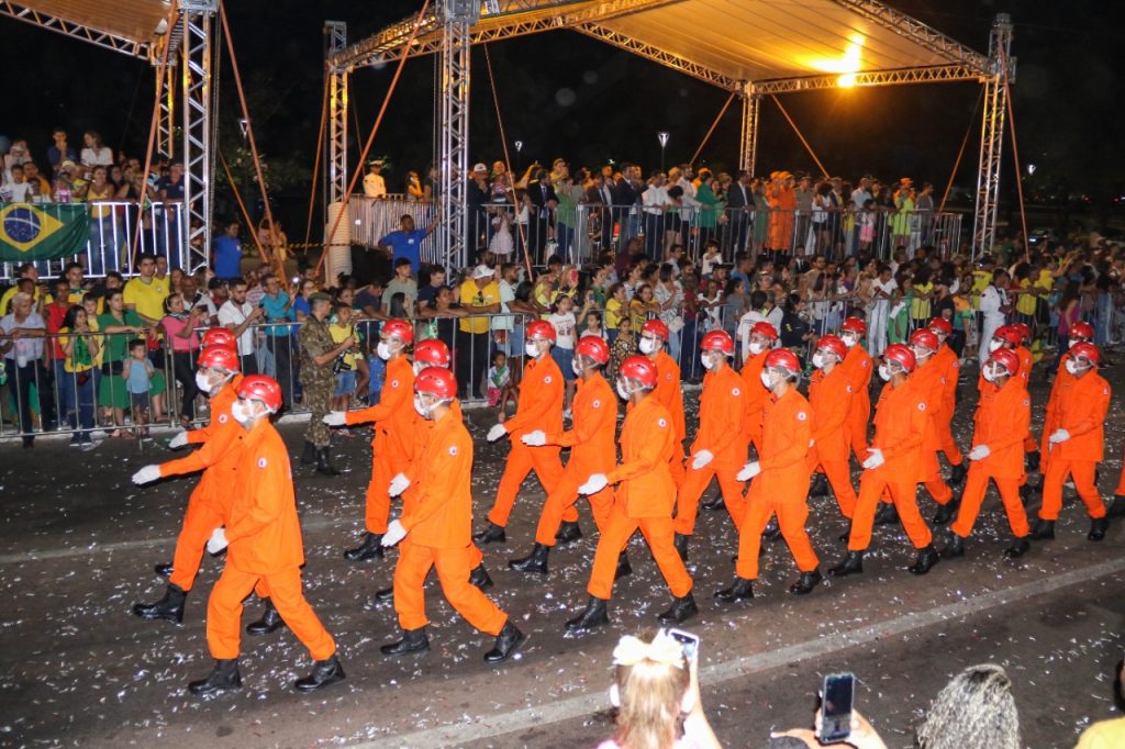 Portal Jaciara Barros – Integrantes do Corpo de Bombeiros Militar desfilam à noite diante do público durante um desfile cívico-militar. – Portal Jaciara Barros