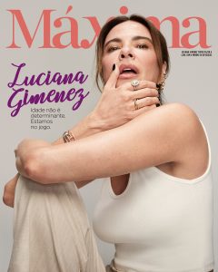 Portal Jaciara Barros – Luciana Gimenez posa de top branco sem mangas diante de capa de revista com a frase "estamos no jogo" em português. – Portal Jaciara Barros