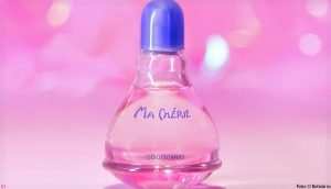 Portal Jaciara Barros – Frasco de perfume rosa com tampa azul e rótulo "cherie" é destacado sobre fundo rosa suavemente desfocado. – Portal Jaciara Barros
