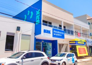 Portal Jaciara Barros – Dois carros estão estacionados em frente à unidade de atendimento da BRK Gurupi, que exibe uma placa de Atendimento ao público. – Portal Jaciara Barros