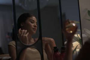 Portal Jaciara Barros – Uma mulher sentada à penteadeira segura um frasco de perfume e pensa no amor no coração do Brasil. – Portal Jaciara Barros