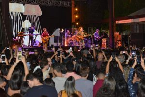 Portal Jaciara Barros – Banda se apresenta à noite no Festival Gastronômico de Taquaruçu enquanto o público assiste e registra o momento em fotos. – Portal Jaciara Barros