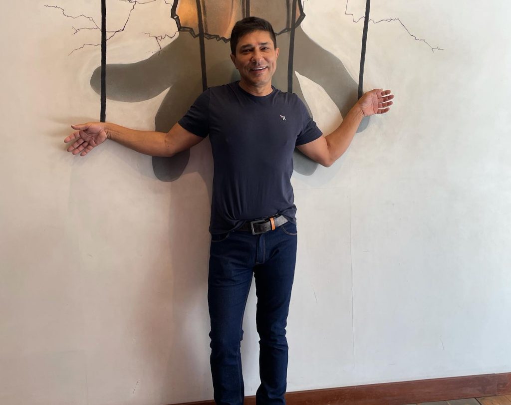 Portal Jaciara Barros – O empresário Wilson Charles Seixas posa diante de uma parede com cordas de fantoche pintadas, sugerindo ter sido manipulado. – Portal Jaciara Barros