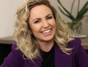 Portal Jaciara Barros – Mulher de cabelos cacheados loiros sorri com blazer roxo; valores ESG impulsionam sua atuação no mercado corporativo. – Portal Jaciara Barros