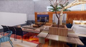 Portal Jaciara Barros – Quarto de hotel moderno com móveis elegantes, árvore central decorativa e placa da HOTELCOR na parede dos fundos. – Portal Jaciara Barros