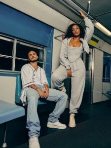 Portal Jaciara Barros – Duas pessoas com roupas casuais posam em um vagão de metrô vazio, sugerindo uma gravação ou celebração especial. – Portal Jaciara Barros