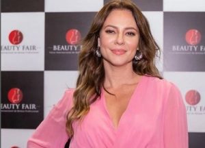 Portal Jaciara Barros – Em um vestido rosa, mulher sorri durante a Beauty Fair ao promover a democratização de cosméticos naturais. – Portal Jaciara Barros