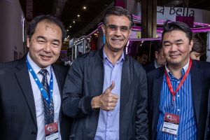 Portal Jaciara Barros – Três influenciadores digitais com crachás participam da Beauty Fair; o homem ao centro sorri e faz sinal de positivo. – Portal Jaciara Barros