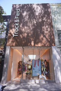 Portal Jaciara Barros – A Fachada da Track&Field Experience Store na Oscar Freire exibe letreiro vertical, entrada de vidro e pôster junto à porta. – Portal Jaciara Barros
