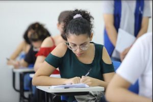 Portal Jaciara Barros – Aluno de óculos anota em caderno durante aula na Unitins enquanto se prepara para o vestibular 2023. – Portal Jaciara Barros