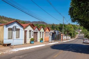 Portal Jaciara Barros – Casas coloridas com telhados inclinados ocupam uma rua tranquila, próximas a pousadas de Taquaruçu sob céu azul claro. – Portal Jaciara Barros