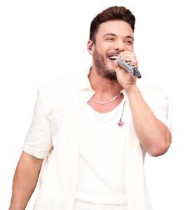 Portal Jaciara Barros – Homem de camisa branca canta sorrindo ao microfone no Garota VIP Belém, usando monitor auricular visível. – Portal Jaciara Barros