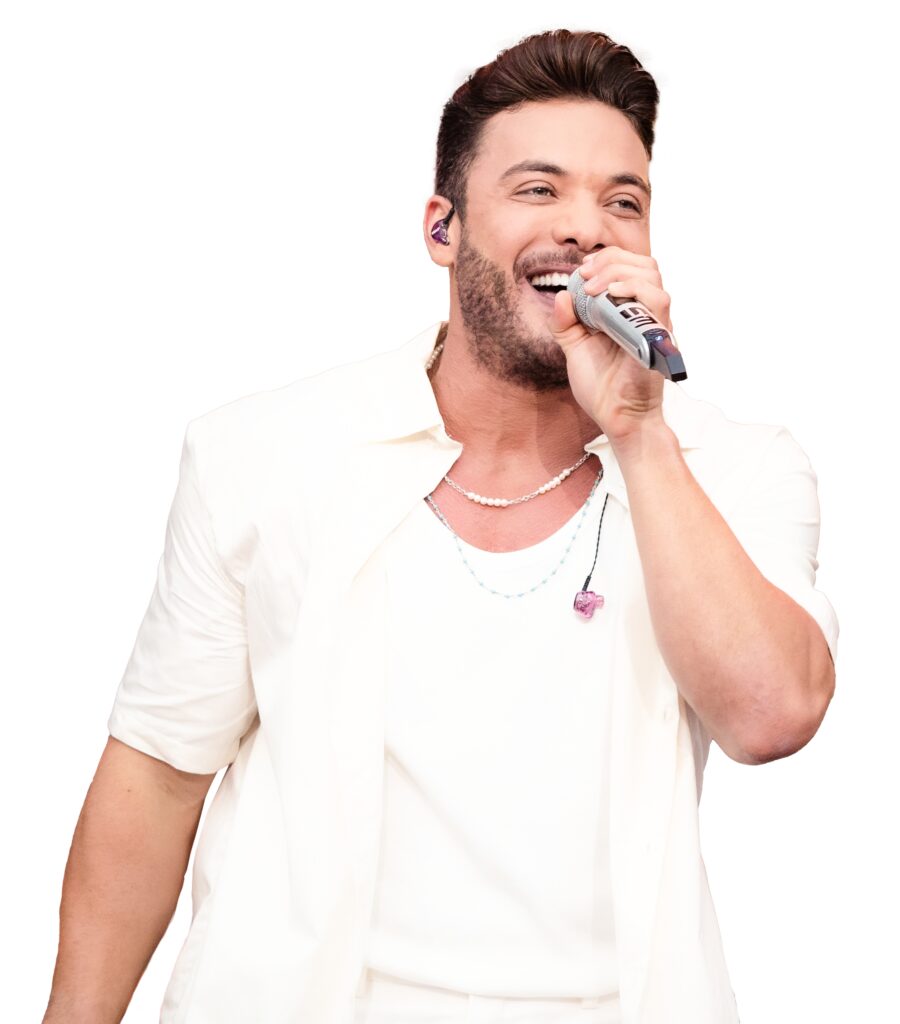 Portal Jaciara Barros – Homem de camisa branca canta sorrindo ao microfone no Garota VIP Belém, usando monitor auricular visível. – Portal Jaciara Barros