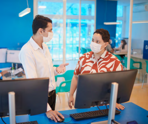 Portal Jaciara Barros – Atendimento da BRK: duas pessoas de máscara conversam em um balcão, em ambiente moderno e bem iluminado. – Portal Jaciara Barros