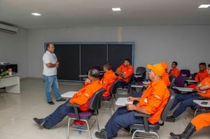 Portal Jaciara Barros – Um homem fala para brigadistas de uniforme laranja em sala de aula; todos ouvem com atenção. – Portal Jaciara Barros