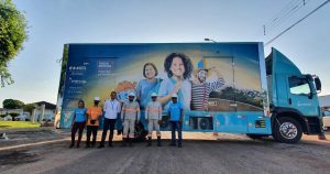 Portal Jaciara Barros – Sete pessoas posam diante de um caminhão azul que divulga a Olimpíada Nacional de Eficiência Energética e inscrições. – Portal Jaciara Barros