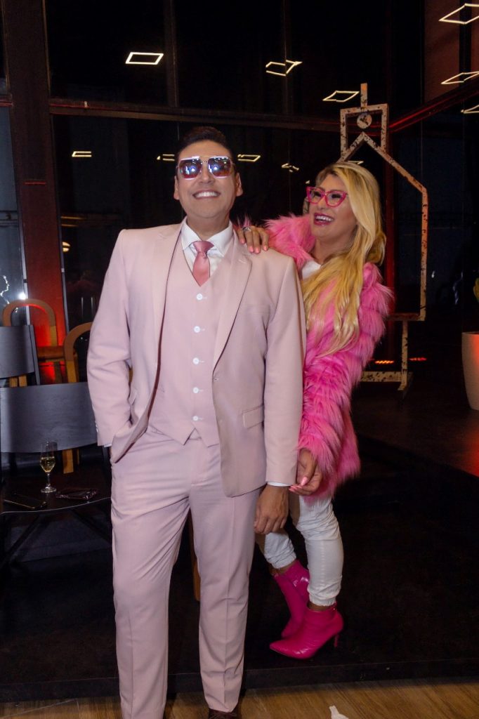 Portal Jaciara Barros – Duas pessoas vestidas de rosa sorriem na Mostra EliteDesign 2022, em looks inspirados no estilo Barbie Gaúcha. – Portal Jaciara Barros