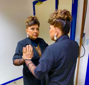 Portal Jaciara Barros – Uma mulher veste roupa preta e é observada diante do espelho, em referência a uma edição especial do Domingão com Huck. – Portal Jaciara Barros