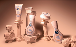 Portal Jaciara Barros – Quatro frascos da linha Amend Millenar Óleos Gregos estão posicionados sobre colunas brancas com fundo pêssego. – Portal Jaciara Barros