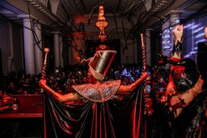 Portal Jaciara Barros – Fantasiado, o participante se apresenta no palco do HALLOWEEN DO COPA diante do público em um salão decorado e iluminado. – Portal Jaciara Barros