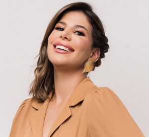 Portal Jaciara Barros – Mulher de cabelos castanhos na inauguração do Instituto Illa Flores, sorri para a câmera usando blusa marrom. – Portal Jaciara Barros