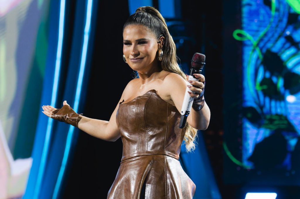 Simone cantora, vestindo uma roupa de couro marrom