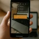 Pessoa segurando celular com Instagram aberto e mensagem sobre a remoção da opção de salvar stories.